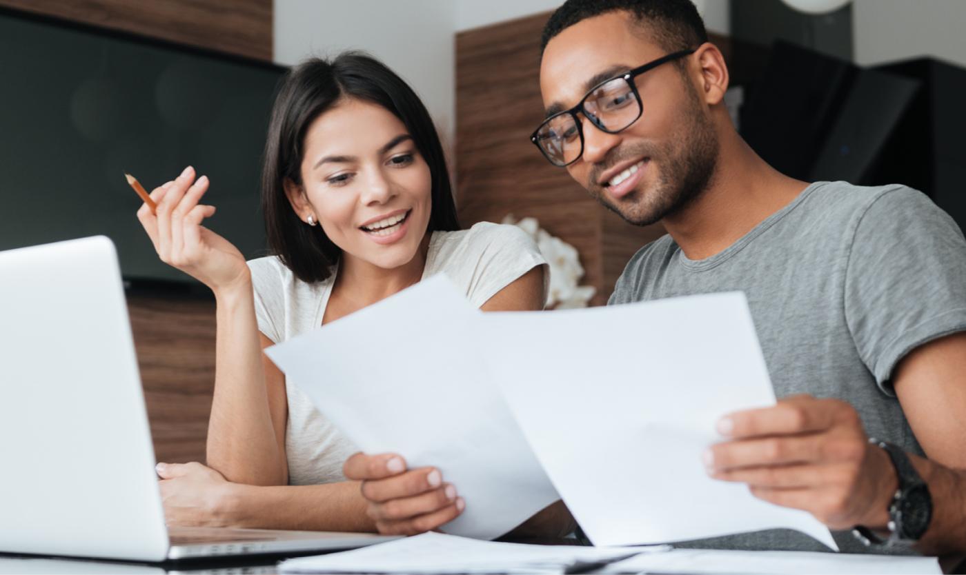 Man en vrouw werkend aan een laptop met documenten in de hand