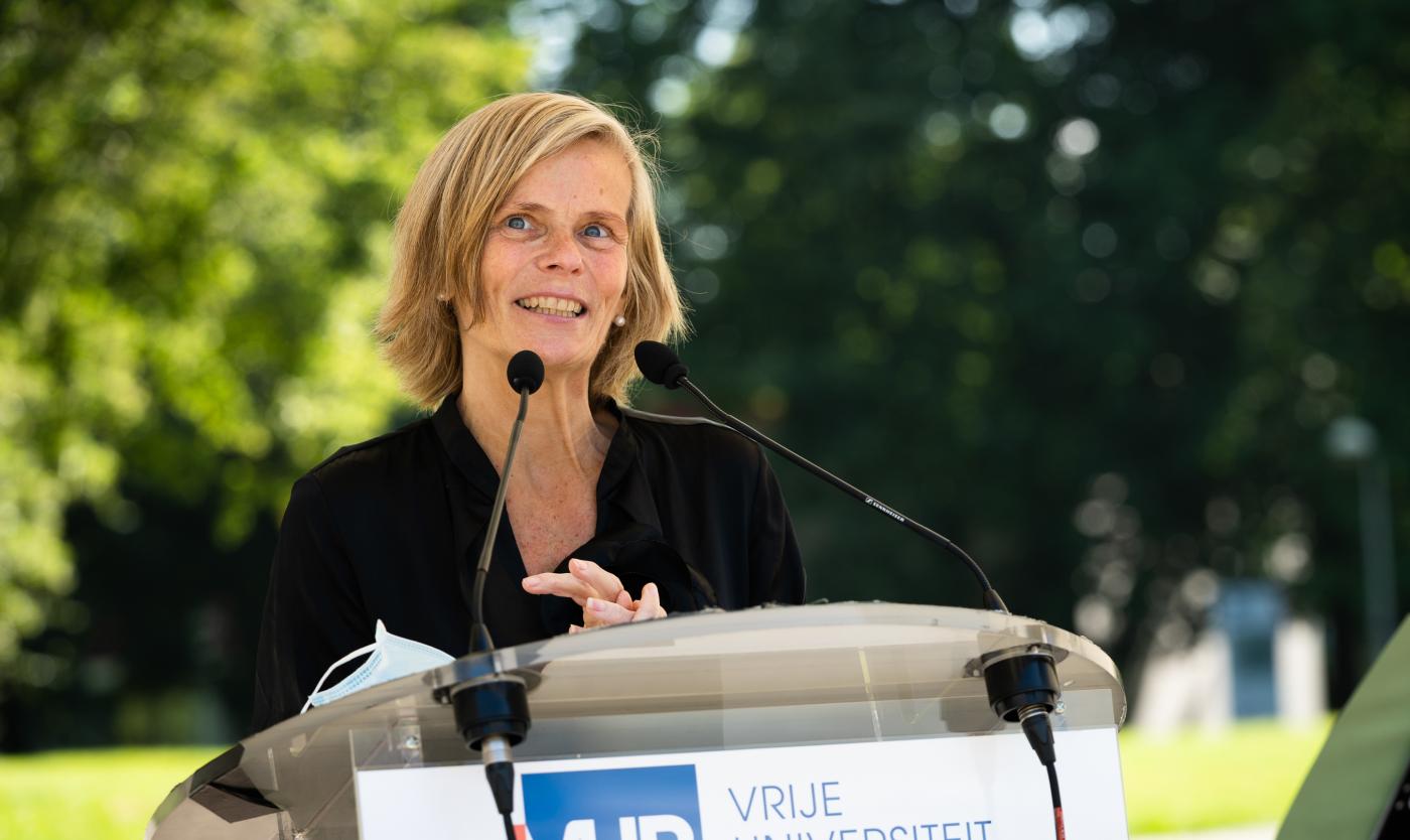 Caroline Pauwels aan het praten met microfoon voor Caroline Pauwels Noodfonds evenement op grasveld van Campus Etterbeek