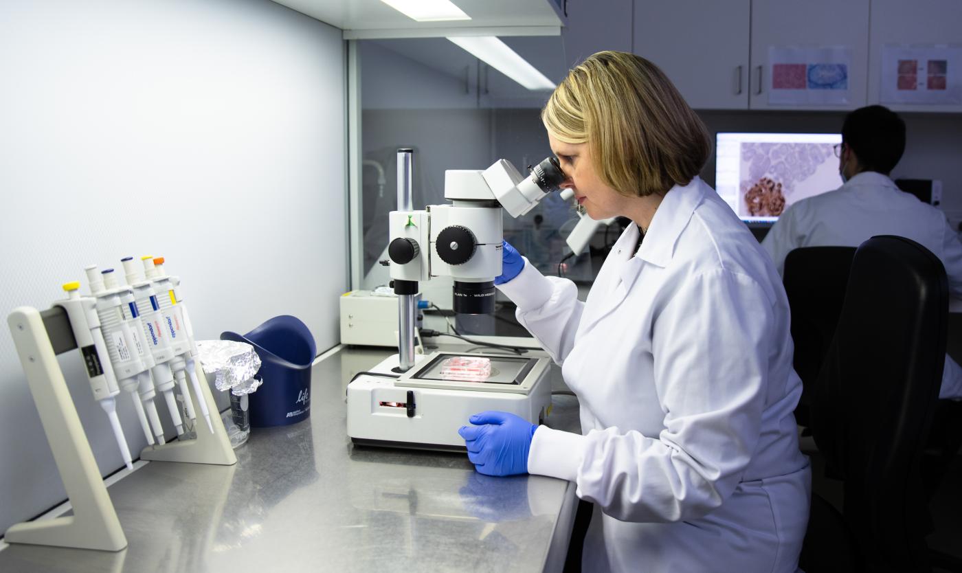 Onderzoek in labo met microscoop voor Wereld Kankerdags bij UZ (Universitair Ziekenhuis Brussel)