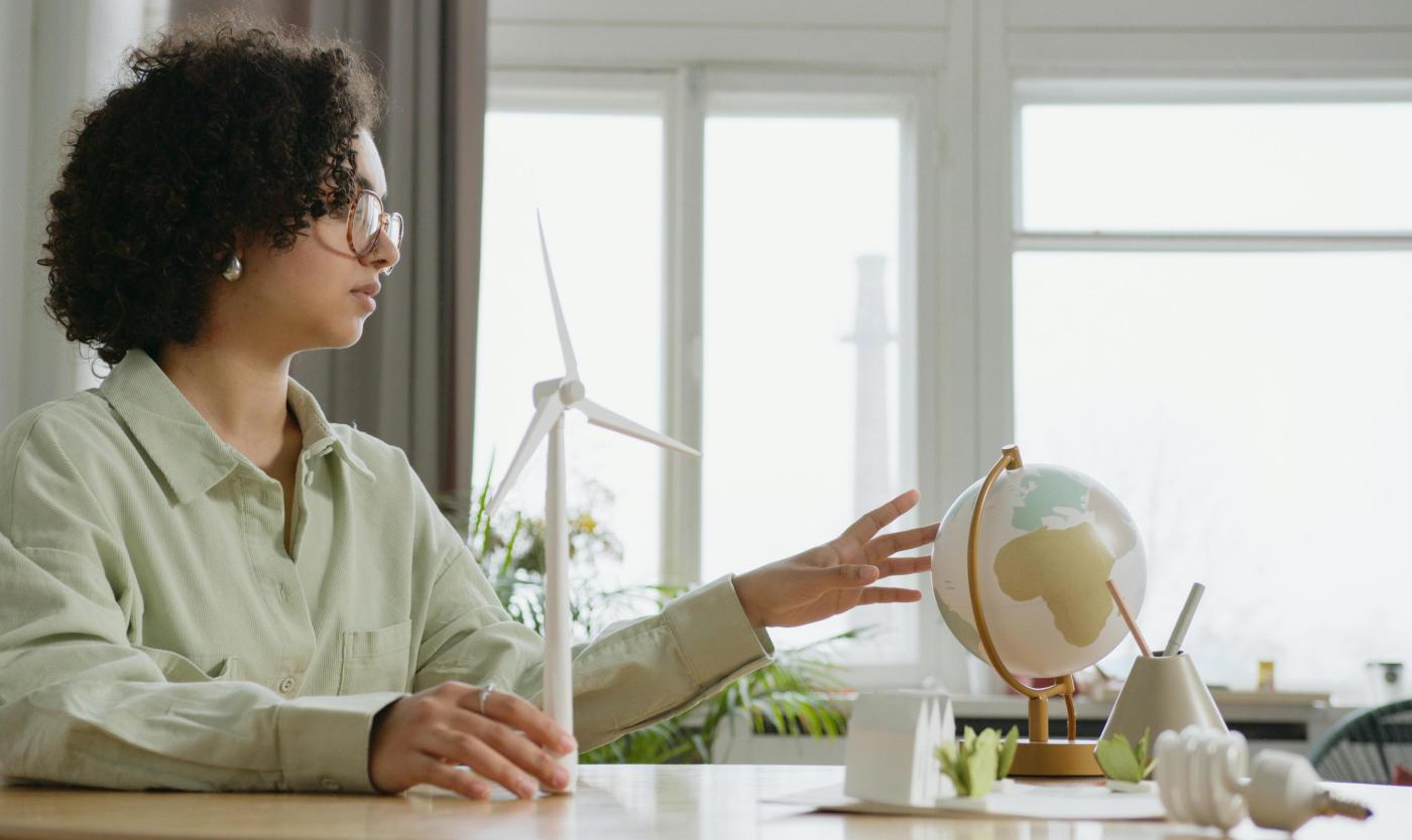 Vrouw met miniatuur windmolen en wereldbol Vrouw met miniatuur windmolen en wereldbol