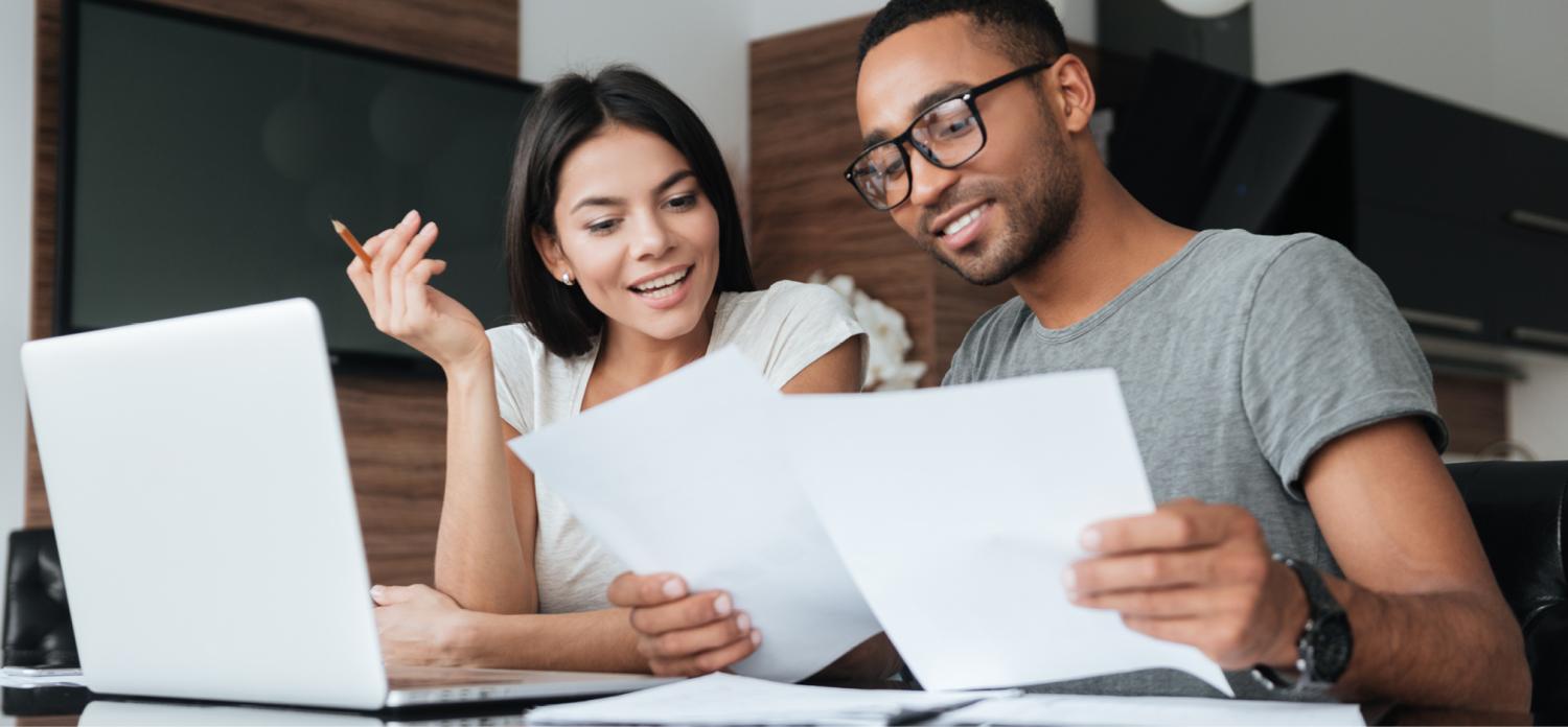 Man en vrouw werkend aan een laptop met documenten in de hand