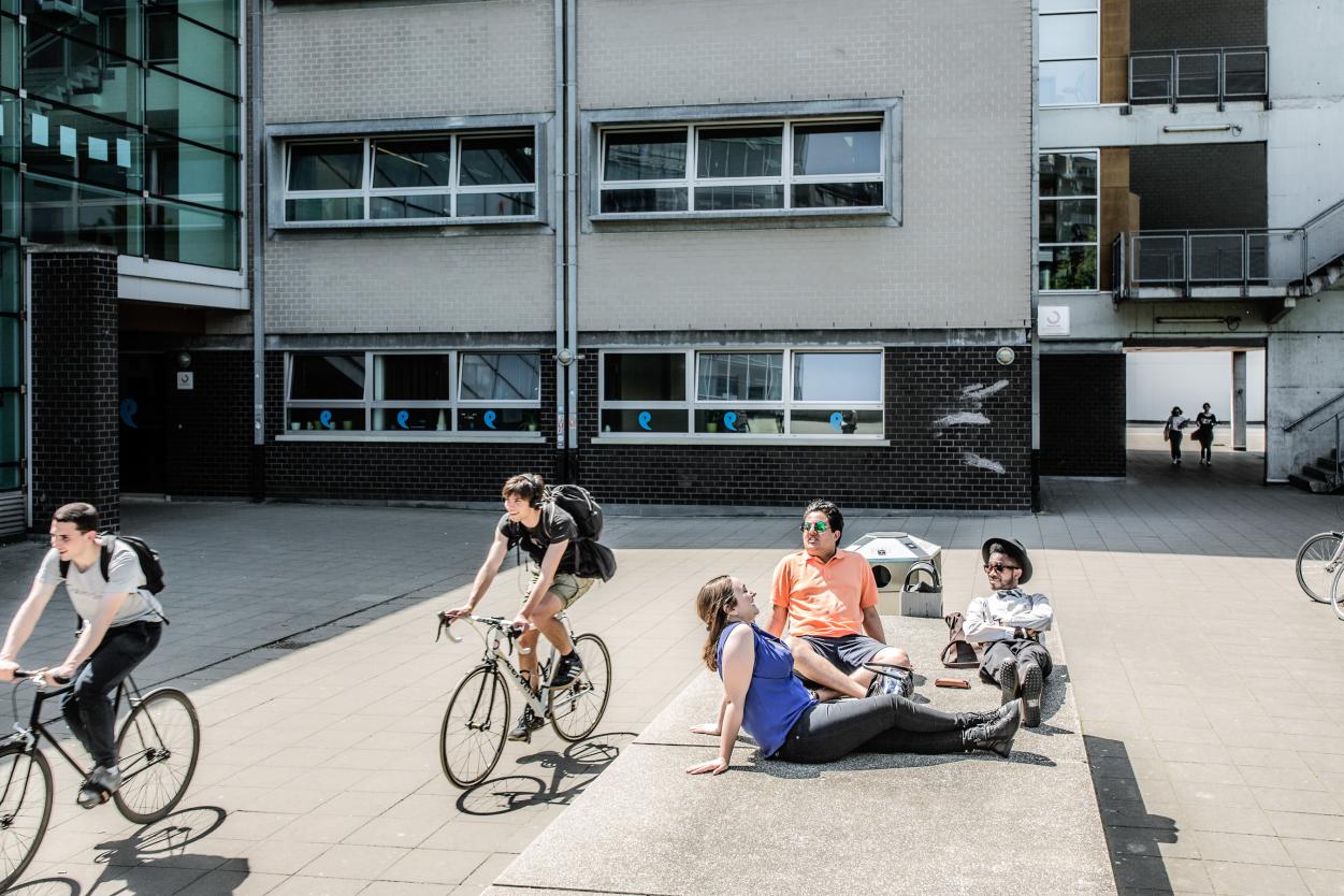 Studenten en fietsers op de esplanade aan het gebouw D op Campus Etterbeek