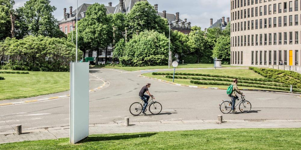 2022_Living Campus Walk_Koning fiets_Twee mannen op de fiets aan het Braemgebouw_Etterbeek_VUB