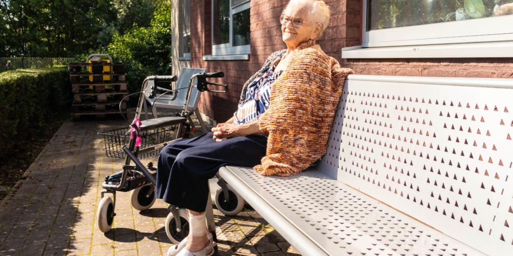 Older woman sitting on bench in the sun